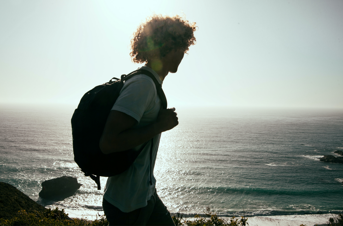 Uomo con capelli ricci che osserva il mare